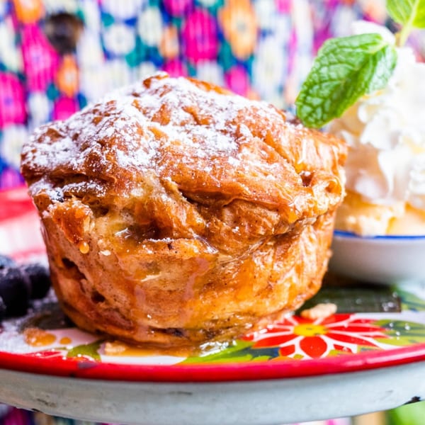 Golden-brown Thai dessert pastry, dusted with powdered sugar, served with whipped cream and mint.
