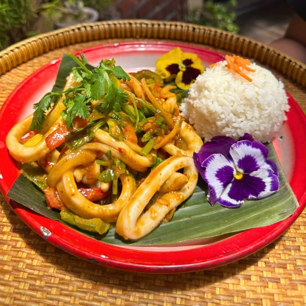 Daughter Thai Kitchen's spicy squid stir-fry with rice, garnished with cilantro and edible flowers.