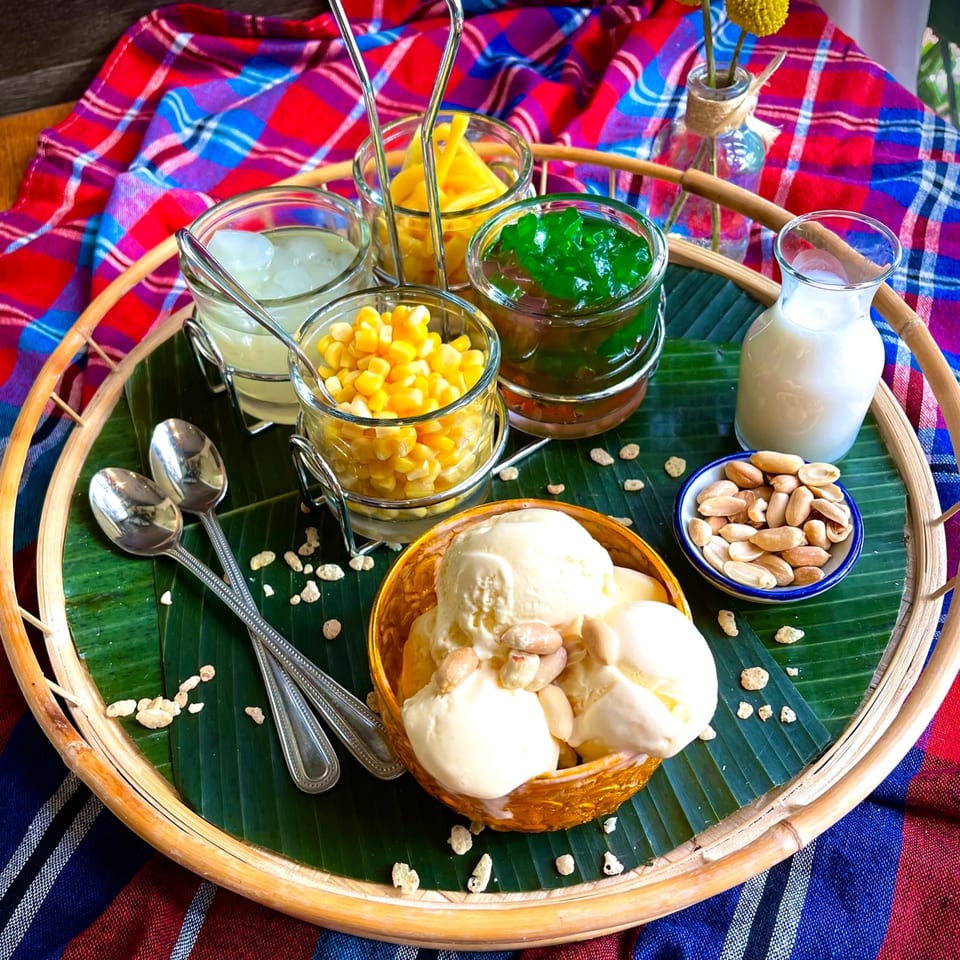 Thai dessert platter with ice cream, corn, jackfruit, green jelly, coconut milk, and peanuts.